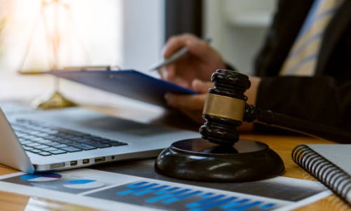 Lawyer working on papers on a table with judge's hammer and gold scales, legal concepts and consultants.